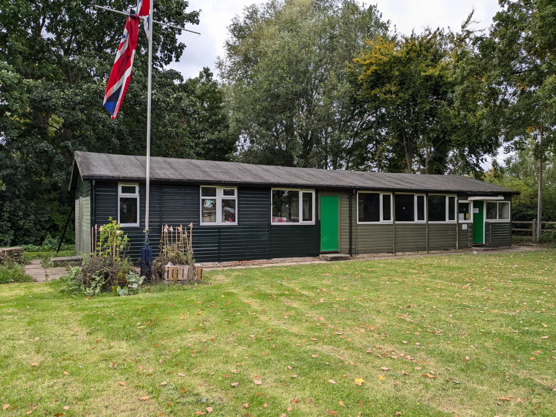 The Osbaldwick and Murton Scout hut, a green timber building beside a grass field with a Union flag flying